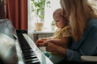 © Westend61 - Mother teaching daughter to play piano at home