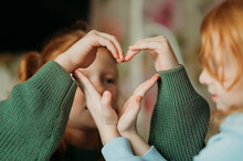 Sisters Making Heart Shape With Hands At Home