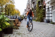 Happy woman riding bicycle on footpath near buildings