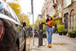 © Westend61 - Smiling woman holding smart phone and charging electric car at station
