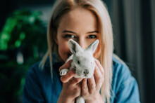 Woman Holding Easter Bunny In Front Of Face At Home