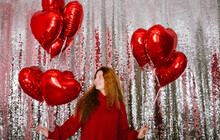 Happy Young Woman Holding Balloons In Front Of Sequin Curtain At Home