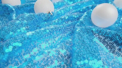 Wall Mural - Christmas light blue background. Glass Christmas bauble on shiny sequin fabric. Slow motion. New Year decoration