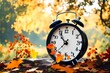 Daylight saving time ends. Alarm clock on beautiful nature background with summer flowers and autumn leaves. Summer time end and fall season coming. Clock turn backward to winter time. Autumn equinox