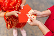 © CandyRetriever  - Chinese lunar new year festival and tradition holiday celebration concept. Happy Asian family grandmother giving red envelope contained money gift with blessing to little grandchild girl in red dress.