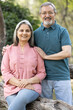 © G-images - Portrait of Indian senior couple embracing while standing in park.