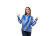 © Ivan Traimak - young caucasian woman with dark hair dressed in a blue striped sweatshirt points her hand to the side on a white background