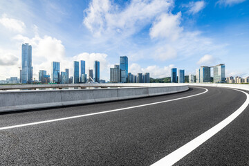 Asphalt highway road and city skyline with modern buildings under blue sky