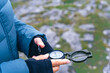 Close up hands of a female hiker with compass with stone and peat background