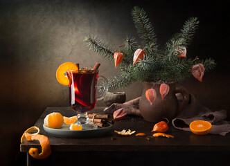 Wall Mural - Winter still life on a dark background. Mulled wine and a bouquet of fir branches with physalis in a clay jug.