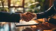 Handshake after reaching a real estate deal. Signing a house rental, mortgage, lease agreement. Real estate agent shakes hands with a client and asks them to legally sign a contract of agreement