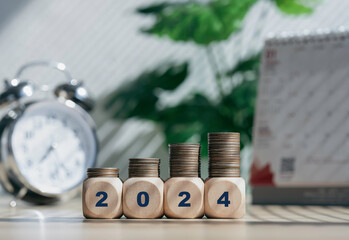 Budget 2024 with blurred office background. Wooden cubes with 2024 and goal icon on coins stack. Countdown to 2024. New year start concept..