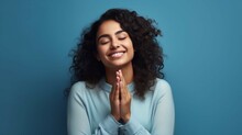 Young Beautiful Hispanic Woman Smiling Confident Praying With Hands Together Over Isolated Blue Background
