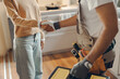 © Daria - Close up of repairman in uniform shaking hands with woman while standing at home kitchen