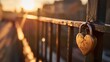 A heart-shaped padlock attached to a bridge railing, bathed in the golden light of sunset, with a blurred cityscape background.