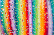 © ADDICTIVE STOCK - Water droplets on a glass surface with a blurred background showcasing a spectrum of colors in vertical lines