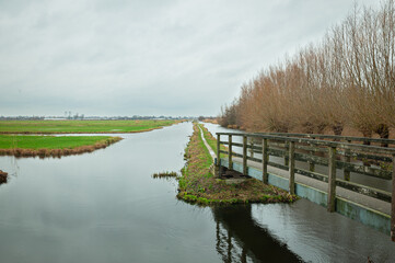 Wall Mural - footbridge in the dutch landscape leading to polder bloemendaal between gouda and waddinxveen, the n