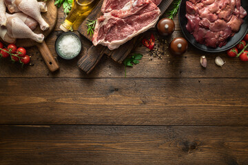 Wall Mural - Set of raw ingredients for preparing food, liver, chicken legs and two beef steaks on a wooden background