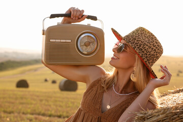 Wall Mural - Happy hippie woman with receiver near hay bale in field