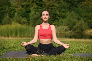 Sticker - Beautiful woman practicing yoga on mat outdoors. Lotus pose