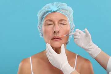 Sticker - Doctor giving lips injection to senior woman on light blue background. Cosmetic surgery