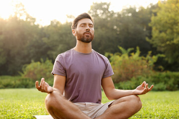 Sticker - Man practicing yoga on mat outdoors. Lotus pose