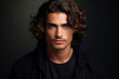Young handsome man with long hair on dark studio background. Face of male model wearing black casual clothes. Concept of style, fashion, beauty, guy portrait, stylish hairstyle