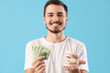 Handsome young man with model of jaw and money on blue background. Dental care concept