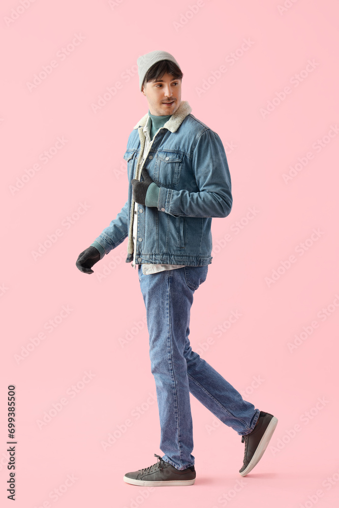 Young man in winter clothes on pink background