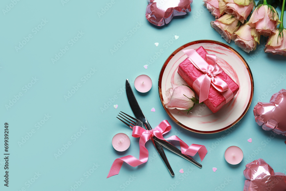 Table setting for Valentine's Day with roses and candles on blue background