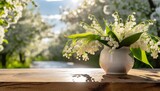 Fototapeta Kwiaty - Konwalie w wazonie na drewnianym blacie. W tle ogród z kwitnącymi na biało drzewami. Wiosenne tło