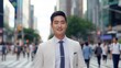 Portrait of a handsome smiling young asian chinese businessman boss in a white suit walking on a city street to his company office. blurry crowdy street background,
