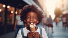A Beautiful Cute Young Black African American Baby Kid Child Boy Model Guy Holding And Eating A Gelato Ice Cream In A Cone Outside In A City On A Sunny Summer Day. Blurred Background
