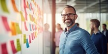 Portrait Of Creative Caucasian Happy Man In Casual Wear Talking And Meeting With Presentation Team Discussing With Colorful Note Paper On Glass White Office With Sunrise Lighting Bokeh