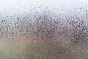 Closeup shot of a steamy window with water drops made in dull day.