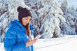 Young Woman using mobile phone in the Winter Mountain 