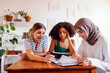 © Dasha Petrenko - Three cute teenage girls do their homework. Caucasian, African American and a Muslim female teens sit at a table with books and notebooks.