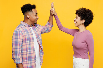 Wall Mural - Young couple two friends family man woman of African American ethnicity wear purple casual clothes meeting together greeting giving high five clapping hands folded isolated on plain yellow background.