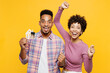 Young winner couple two friends family man woman of African American ethnicity wear purple casual clothes together hold in hand bunch of keys house mockup isolated on plain yellow orange background.