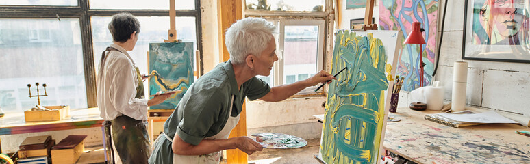 Wall Mural - inspired mature women painting on easels in craft workshop with colorful pictures on walls, banner