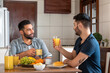brazilian gay couple having breakfast and talking in kitchen table