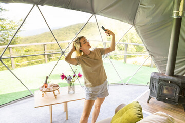 woman with smartphone in dome tent