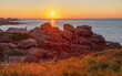 Colorful sunset on the Pink Granite Coast (Cote de Granite Rose), photographer in the field. Ploumanach, Perros-Guirec, Brittany, France.