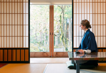 A young caucasian woman is relaxing at a traditional Japanese drinking a tea