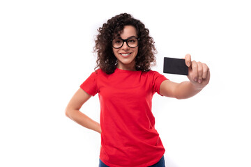 Wall Mural - young smart pretty curly brunette woman dressed in a red t-shirt uses a bank credit card