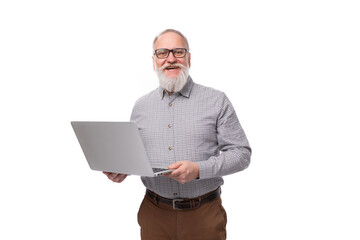 Wall Mural - handsome elderly boss man with a white beard and mustache dressed in a shirt and trousers holds a laptop in his hands for a meeting