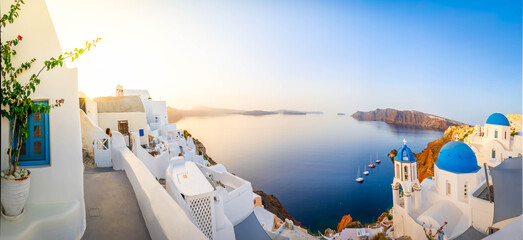 Wall Mural - traditional greek white village Oia of Santorini, with blue domes against Aegan sea and caldera, Greece, web banner format