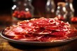 Delicate slices of cured Spanish ham dd over a plate, with their deep red color and marbled fat glistening in the light. The ham has a rich, nutty flavor and melts in your mouth, leaving