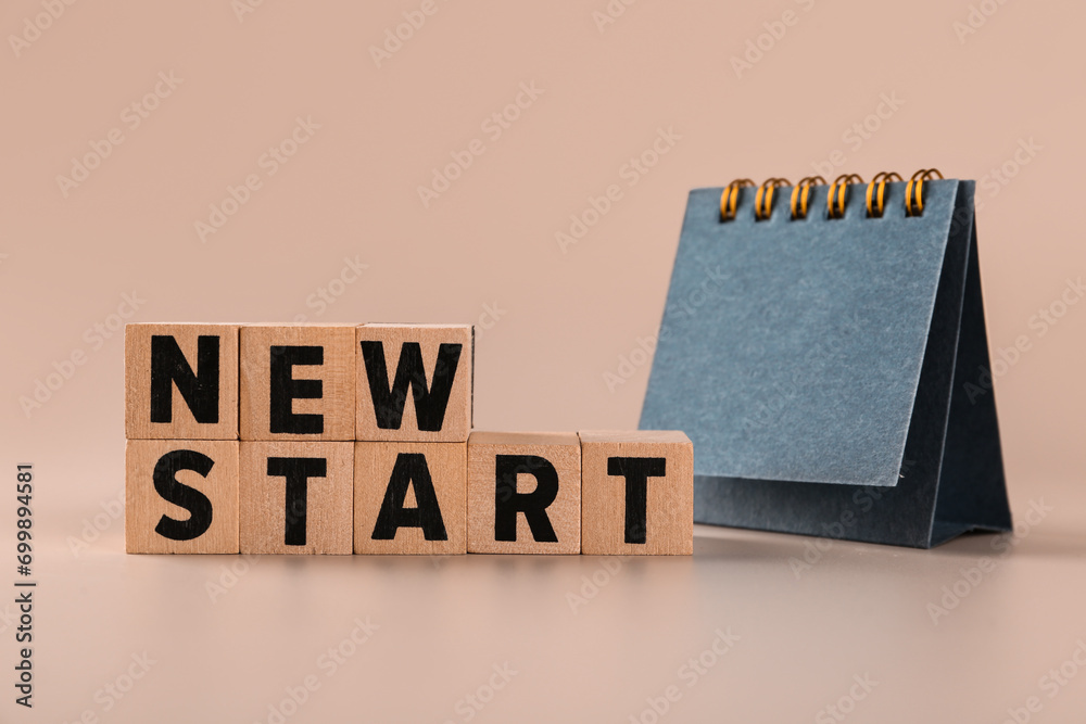Cubes with text NEW START and blank flip calendar on beige background