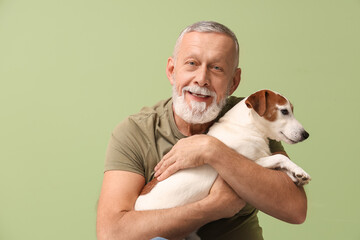 Senior man with cute dog on green background